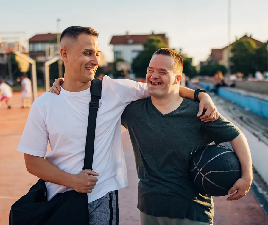 Two men with their arms around each other, laughing as they walk together
