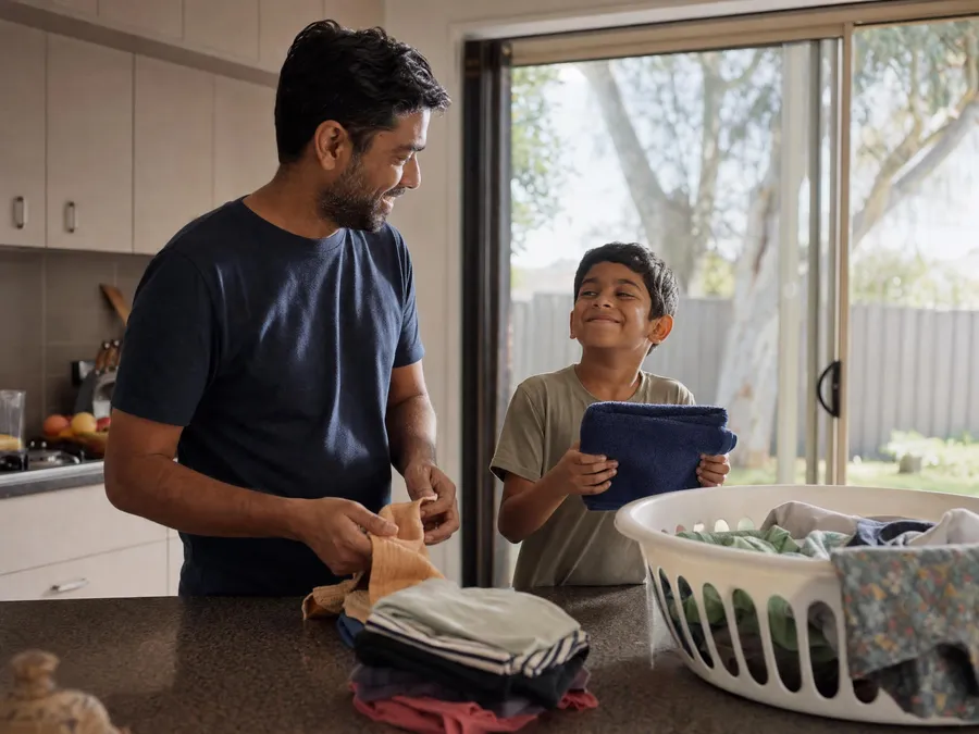 Behaviour support in Bankstown: a father and his young son folding washing together in an Australian home