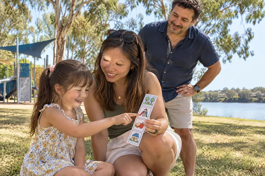 Behaviour support in Penrith: a practitioner and a young girl using a picture schedule at a riverside park