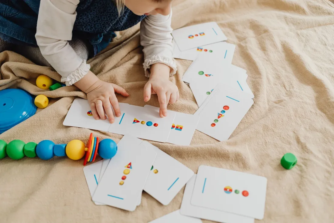 A young child laying out colourful picture cards on a blanket