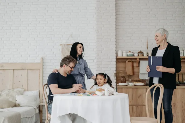 A family at a kitchen table with a child while a practitioner stands alongside