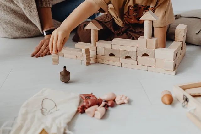 A child playing with wooden blocks and toys on a light floor