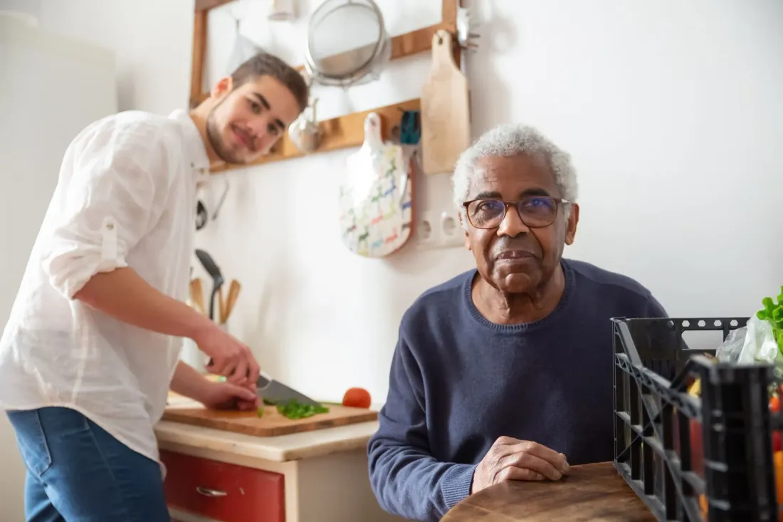 A young man helping an older man prepare vegetables in a kitchen